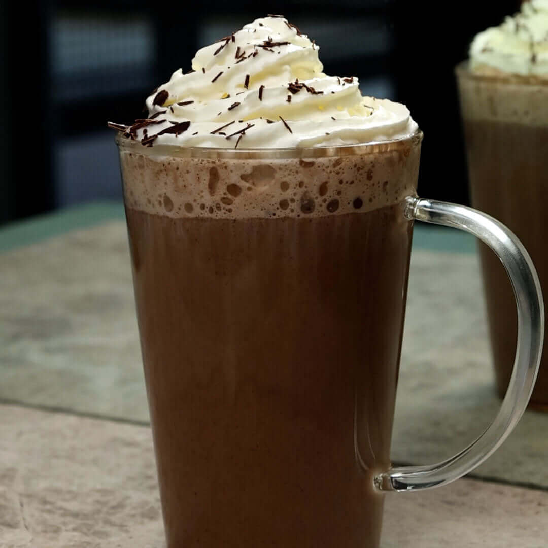 hot chocolate in a mug topped with whipped cream and cocoa powder
