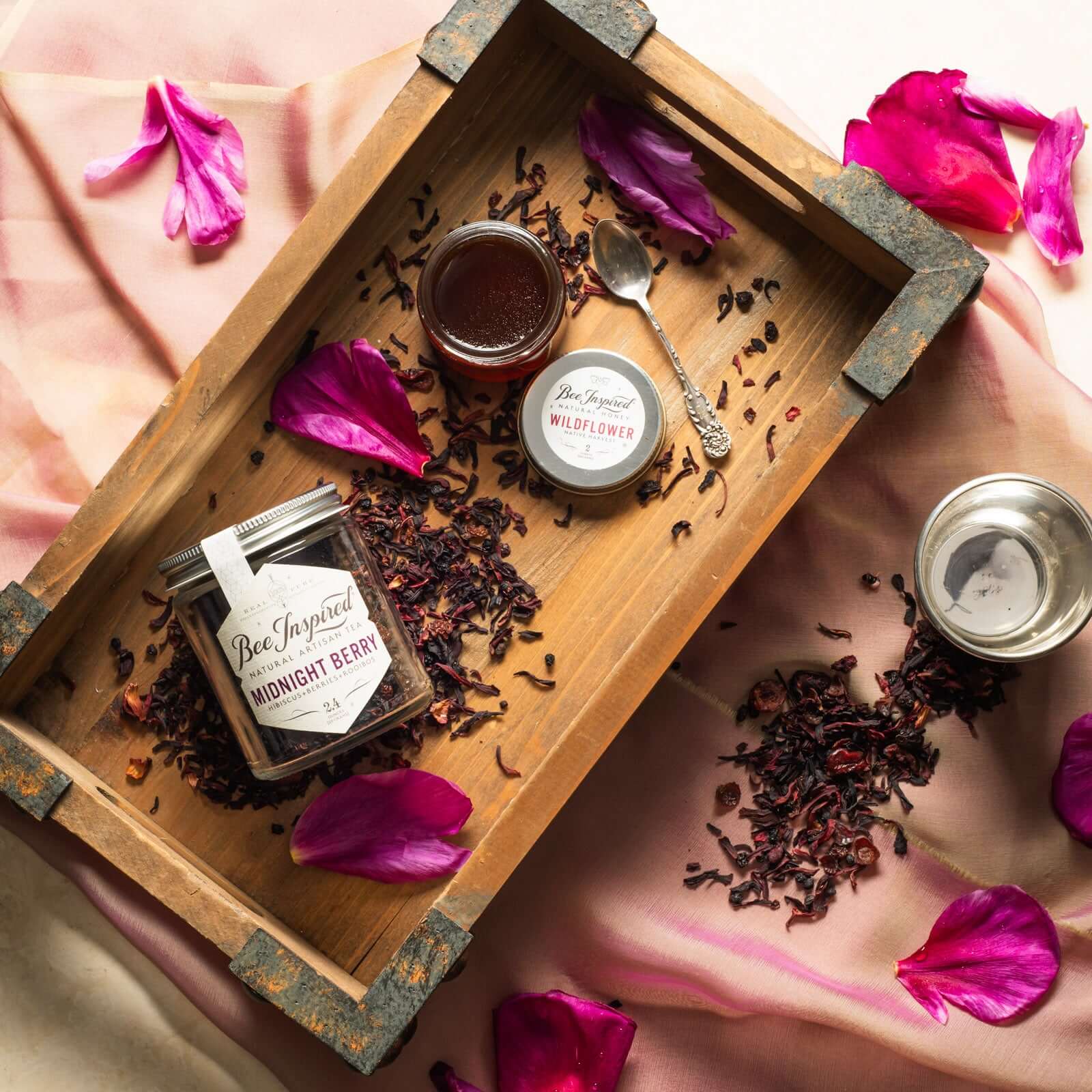 jar of bee inspired midnight berry tea next to wildflower honey on a wooden serving tray