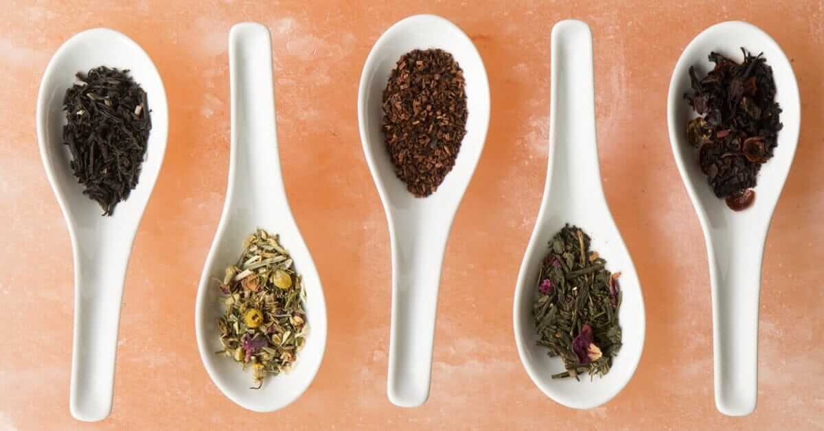 5 white spoons holding different tea varieties