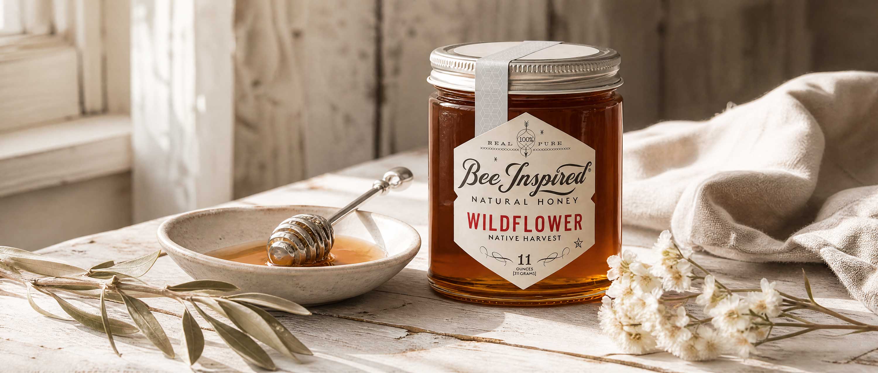 wildflower honey with honey and dish with silver dipper and linens on wood table