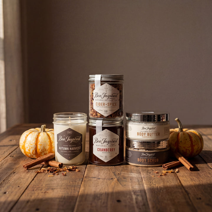Collection of Bee Inspired skincare and candle products on a wooden surface with pumpkins and cinnamon sticks.