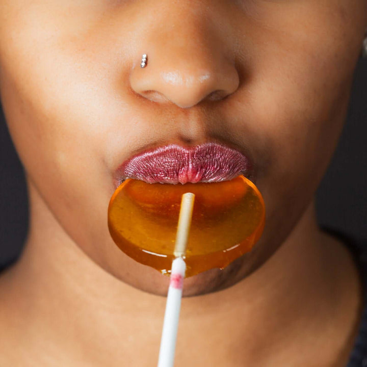 A woman eating a honey lollipop 