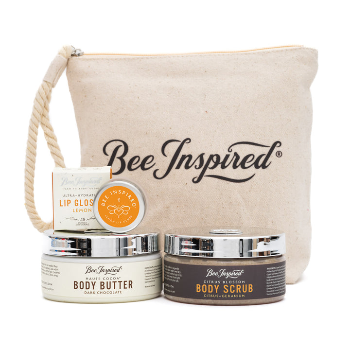 Bee Inspired skincare products including lip gloss, body butter, and body scrub with a canvas bag on a white background.