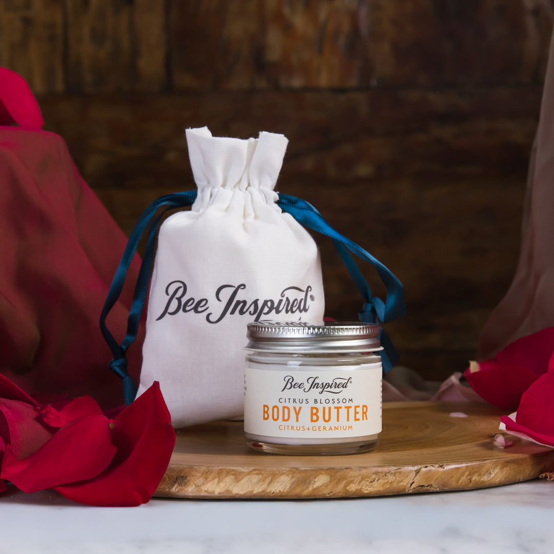 Jar of Bee Inspired body butter on a wooden board with a branded drawstring bag in the background.
