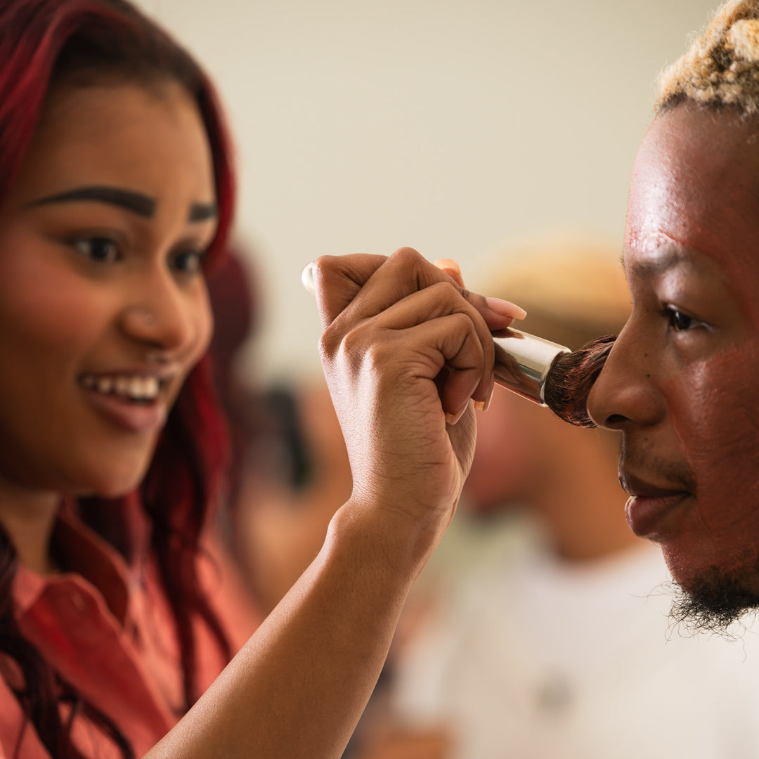 woman brushing bee inspired clarity dry mask onto the face of a man