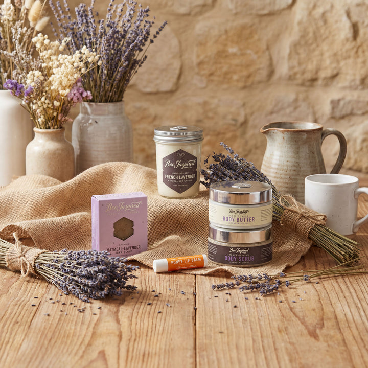 Cosmetic products with lavender on a wooden table against a stone wall.
