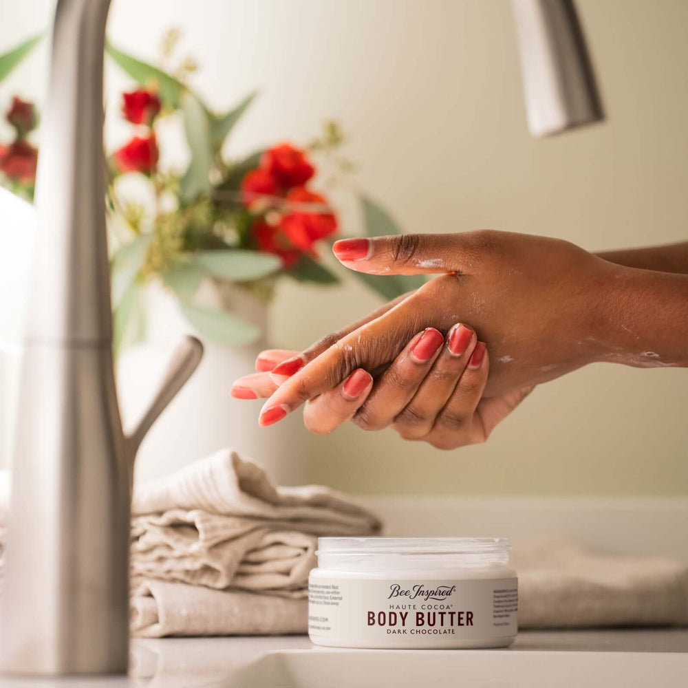 woman using haute cocoa body butter from bee inspired honey retail store in owings mills on her hands next to a sink 