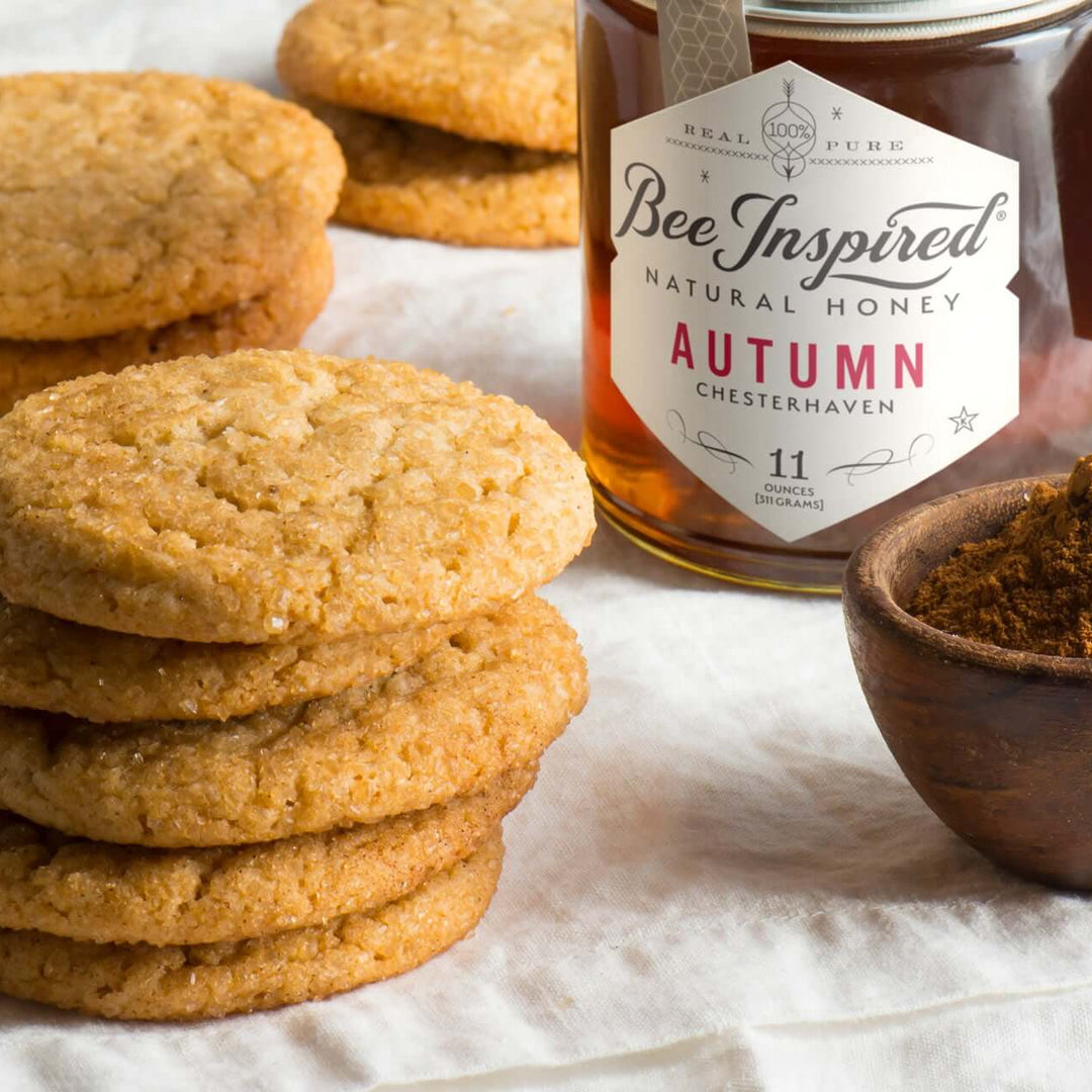 cookies next to a glass of milk, a bowl of ground cinnamon, and a jar of autumn honey from bee inspired honey retail store in owings mills