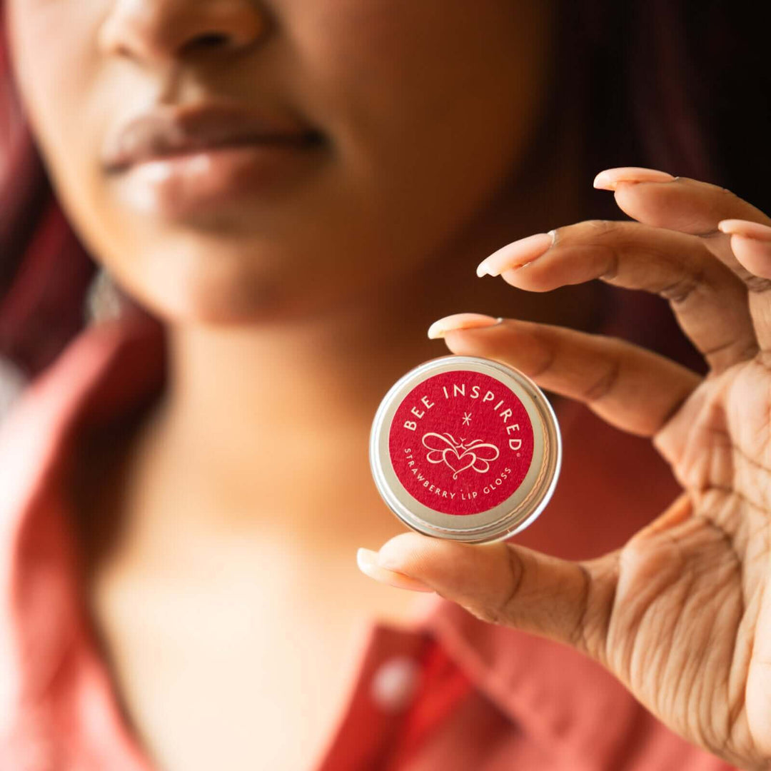A woman holds Bee Inspired strawberry lip gloss 