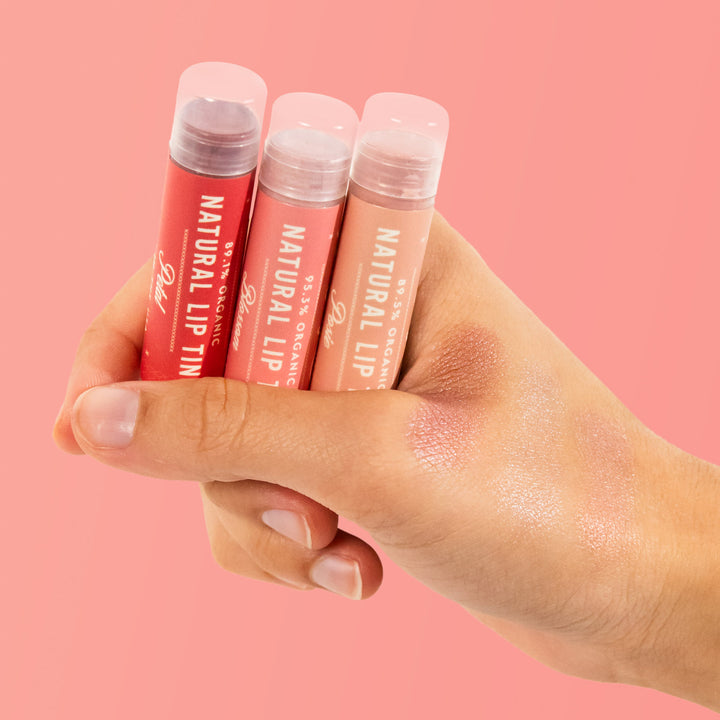 holding Naturals lip tint trio with colors tested on hand