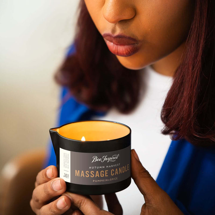 woman blowing out flame of Autumn Harvest massage candle