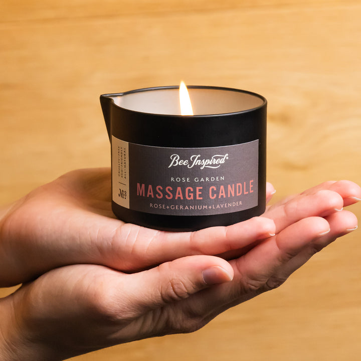 hands holding a lit rose garden massage candle