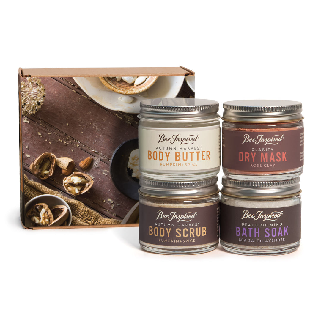 Set of four Bee Inspired skin care products in front of a wooden box with autumn harvest design.