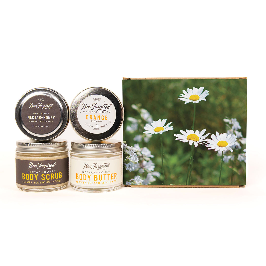 Three jars of Ben Trujillo Natural Products body care products and a matching gift box featuring daisies. The set includes Nectar-Honey body scrub, Orange blossom body butter, and a body scrub with beeswax and honeycomb, all arranged on a white background.