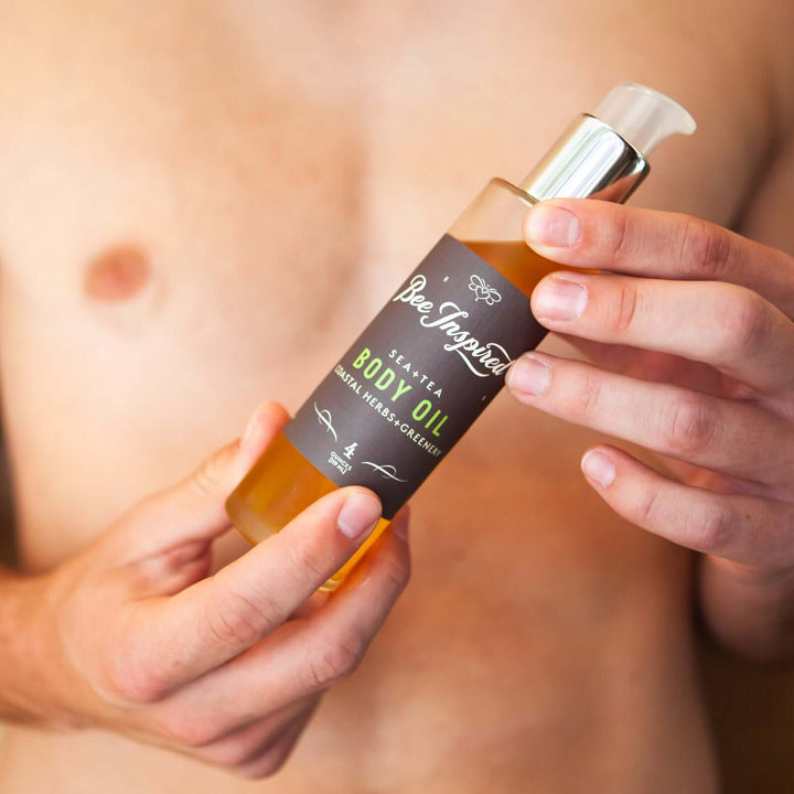 Man holds Sea+Tea body oil in front of his chest 