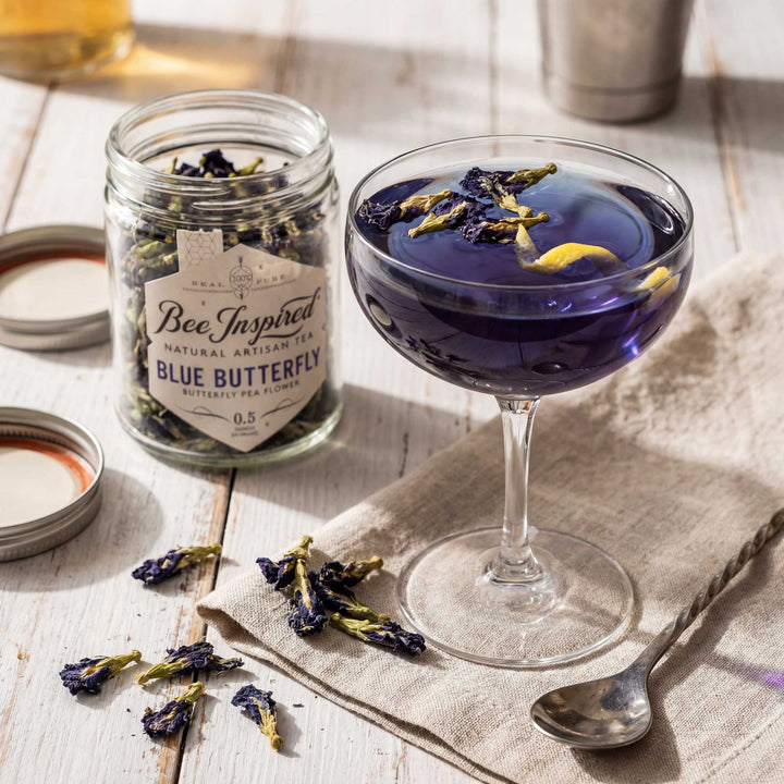 Blue butterfly pea flower tea in a glass with a jar of tea leaves on a wooden surface.