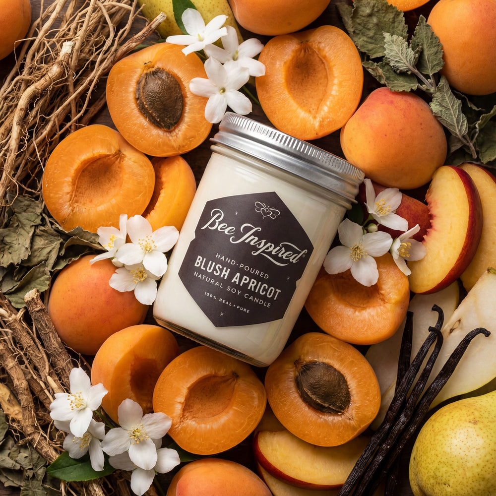 Candle labeled 'Bee Inspired' surrounded by apricots, flowers, and vanilla beans.