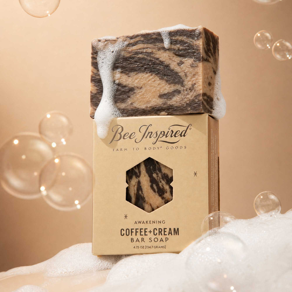 Coffee and cream bar soap with packaging labeled 'Bee Inspired' on a beige background with bubbles.