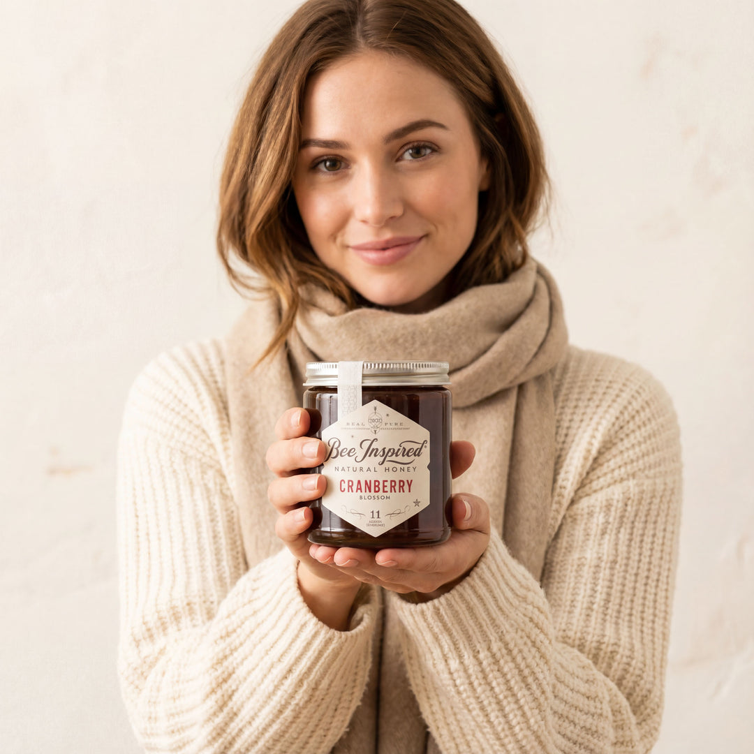 Woman holding a jar of cranberry honey with a neutral background