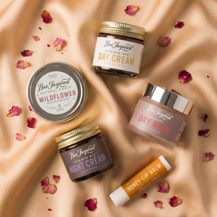 Skincare products including jars and a lip balm on a beige fabric background with dried flowers