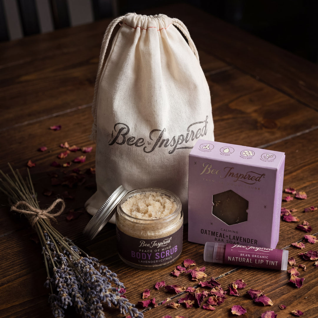 Bee Inspired skincare products on a wooden surface with lavender and a drawstring bag.