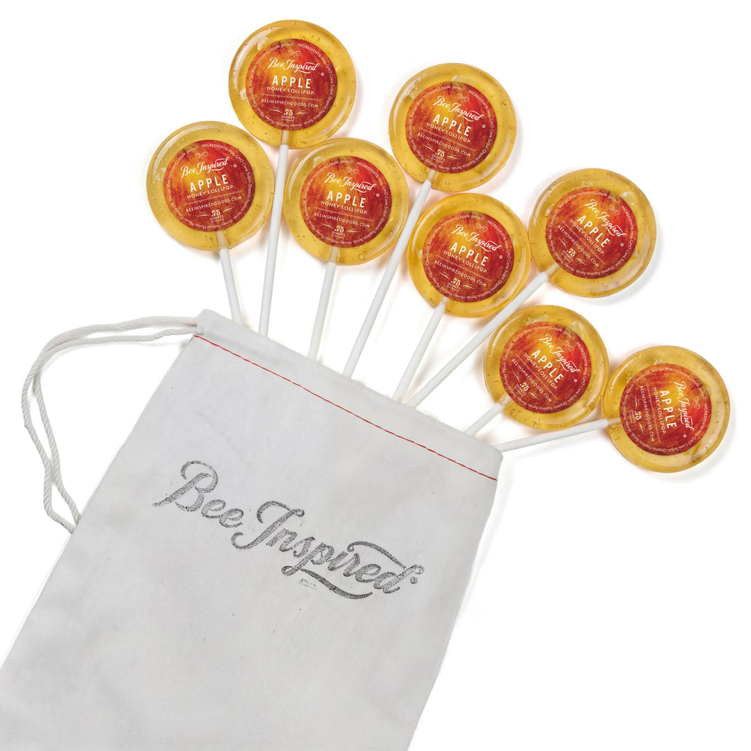 Apple lollipops with a 'Bee Inspired' drawstring bag on a white background