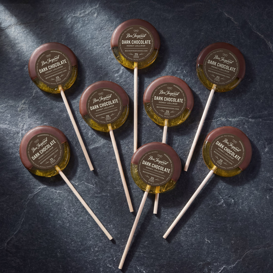 Dark chocolate lollipops with branded labels on a dark surface