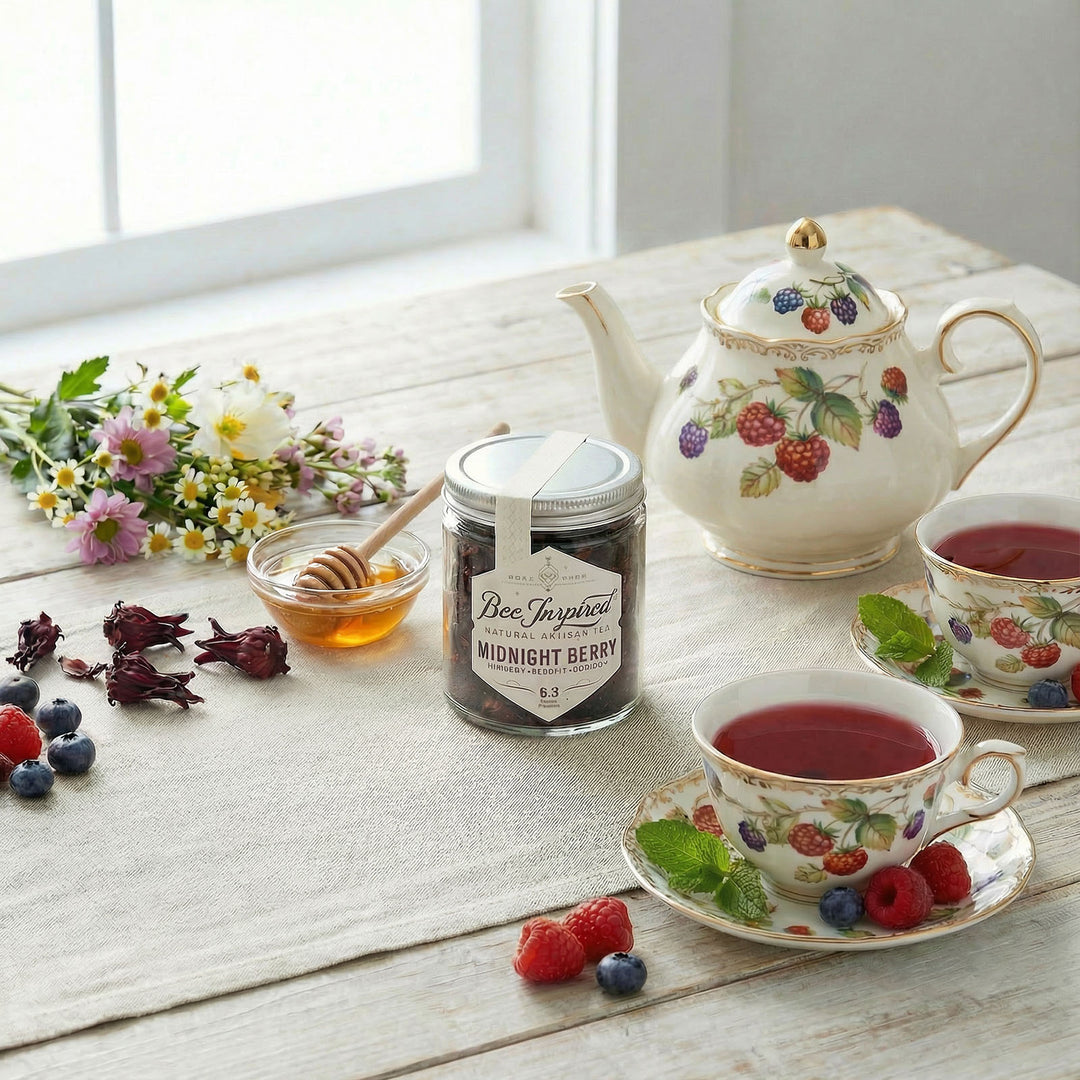 Tea set with teapot, cups, and a jar of honey on a wooden surface with flowers in the background.