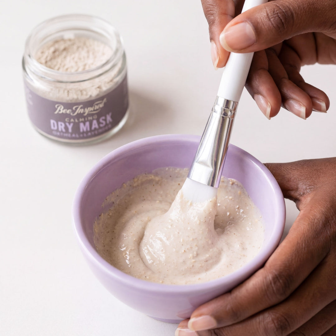 Person mixing dry mask in a bowl with a brush, next to a jar of Bee Inspired Calming Dry Mask.