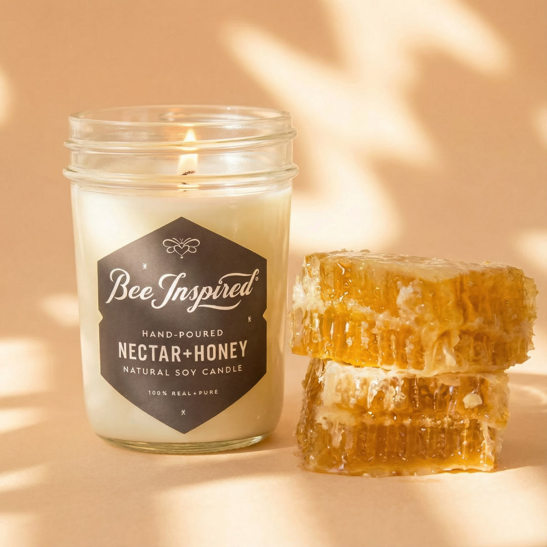 Candle labeled 'Bee Inspired' next to honeycomb on a beige background