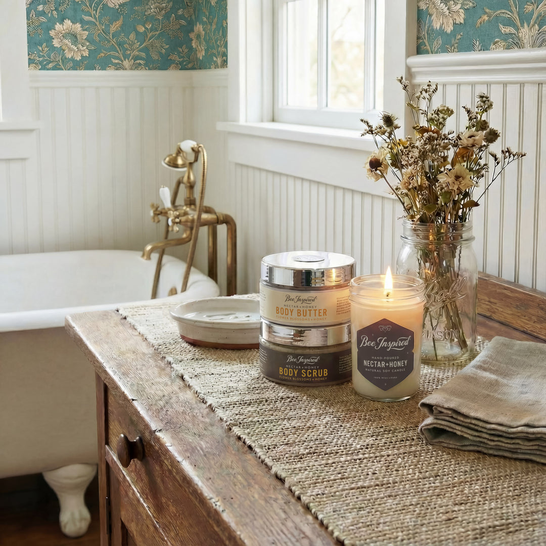 Candle and body care products on a wooden table with floral wallpaper in the background