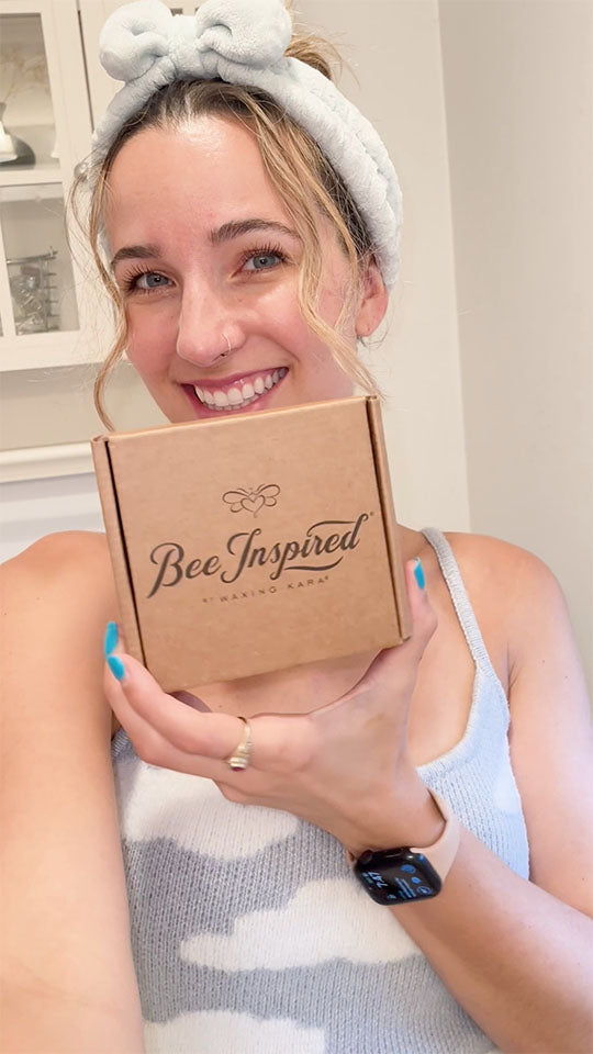Woman holding a 'Bee Inspired' box with a neutral background