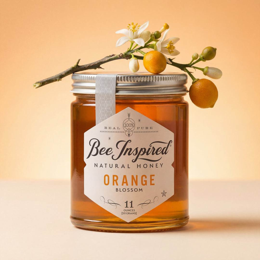 Jar of Bee Inspired Natural Honey with a branch of oranges and flowers on an orange background