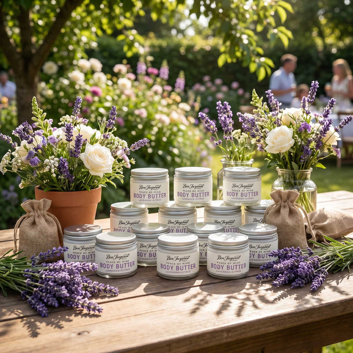 Jars of body butter on a wooden table with flowers and lavender in an outdoor setting