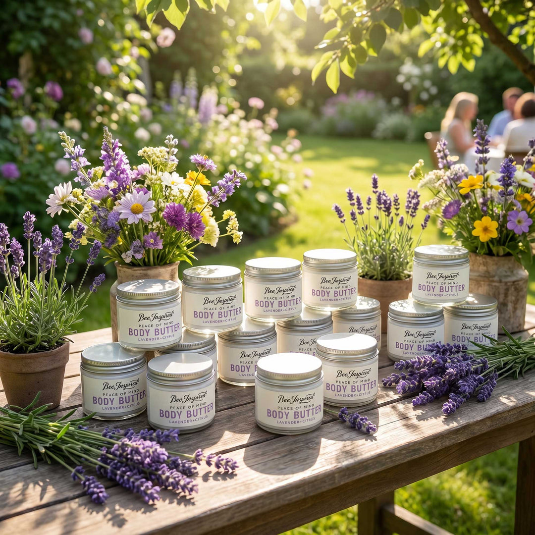 Jars of body butter on a wooden table with flowers and plants in a garden setting