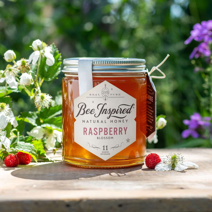 Raspberry honey, raspberry blooms, and honeycomb on outdoor table 