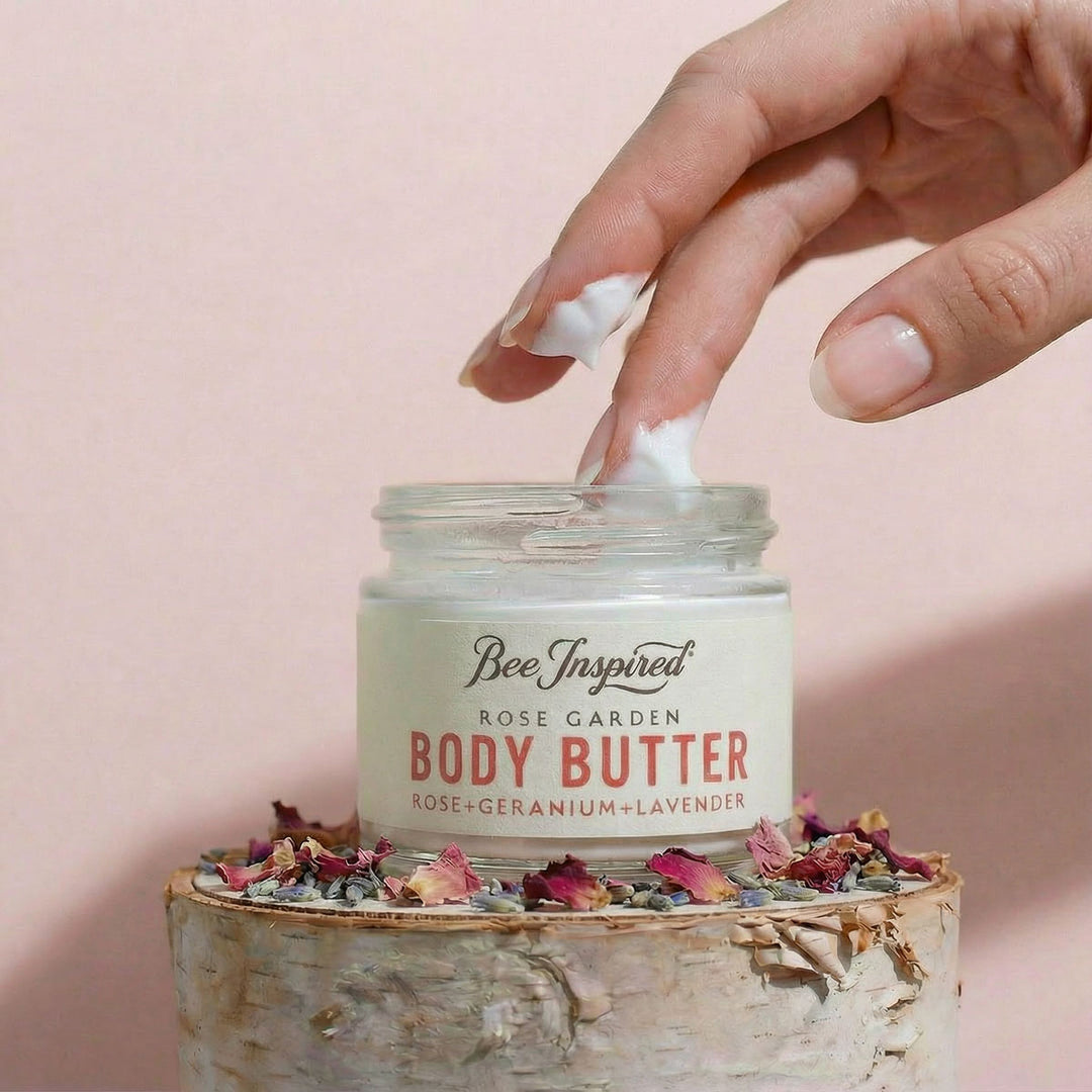 Hand applying body butter from a jar labeled &