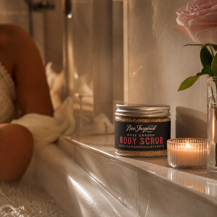 Rose Garden Body Scrub Party Favor jar on a bathroom counter with a candle and rose.