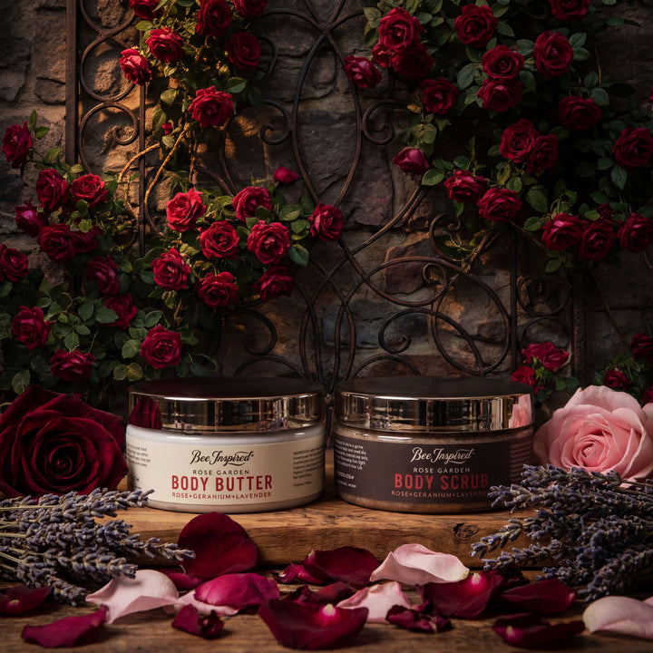 Two jars of Bee Inspired body products on a wooden surface with flowers and petals.