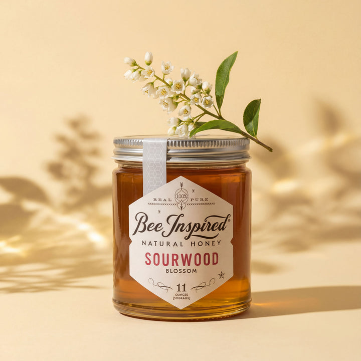 Jar of Bee Inspired natural honey with a label and a sprig of flowers on a beige background