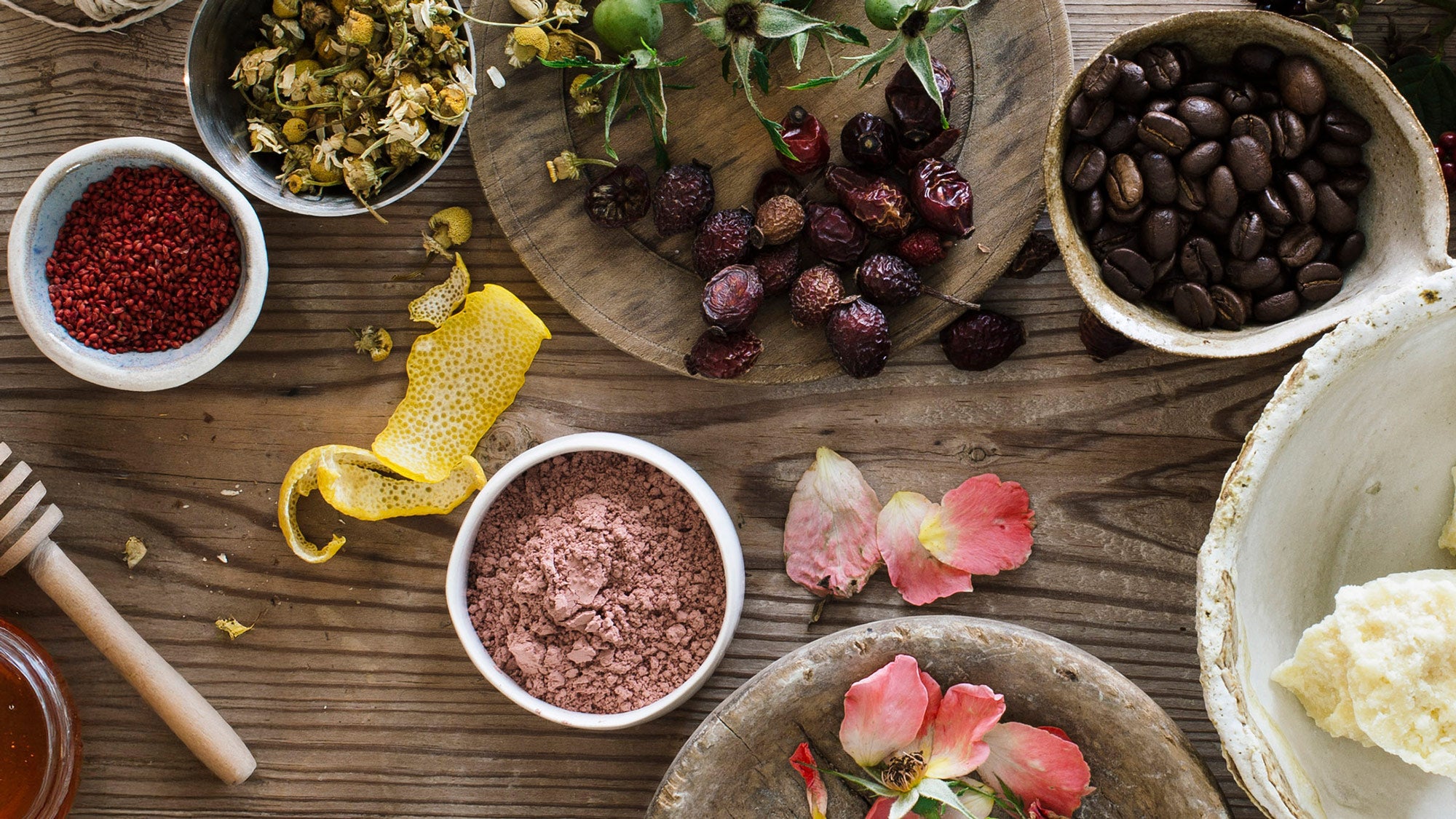 Assorted ingredients including dried fruits, spices, and flowers on a wooden surface.