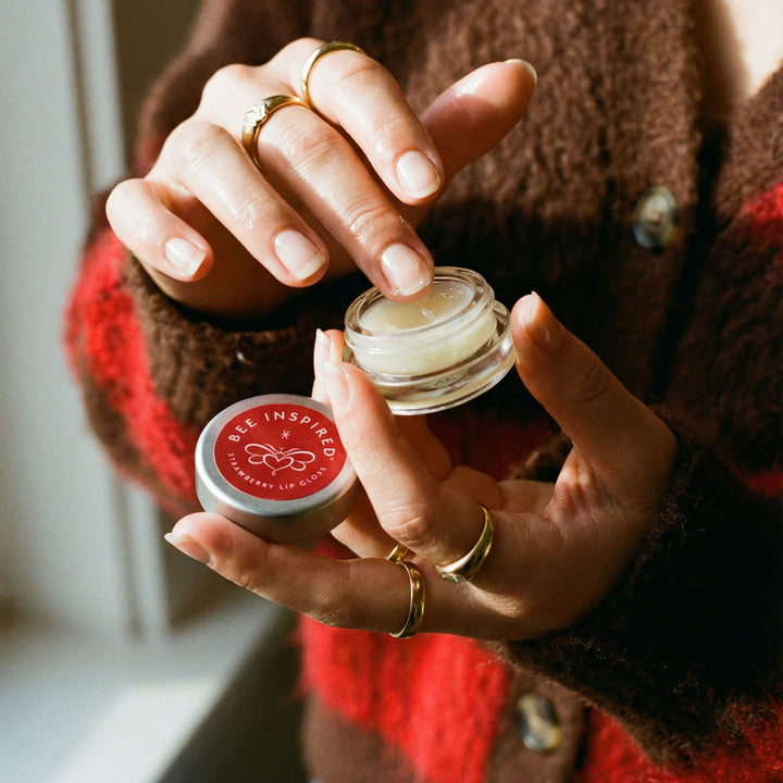 Person holding two lip balm containers with &