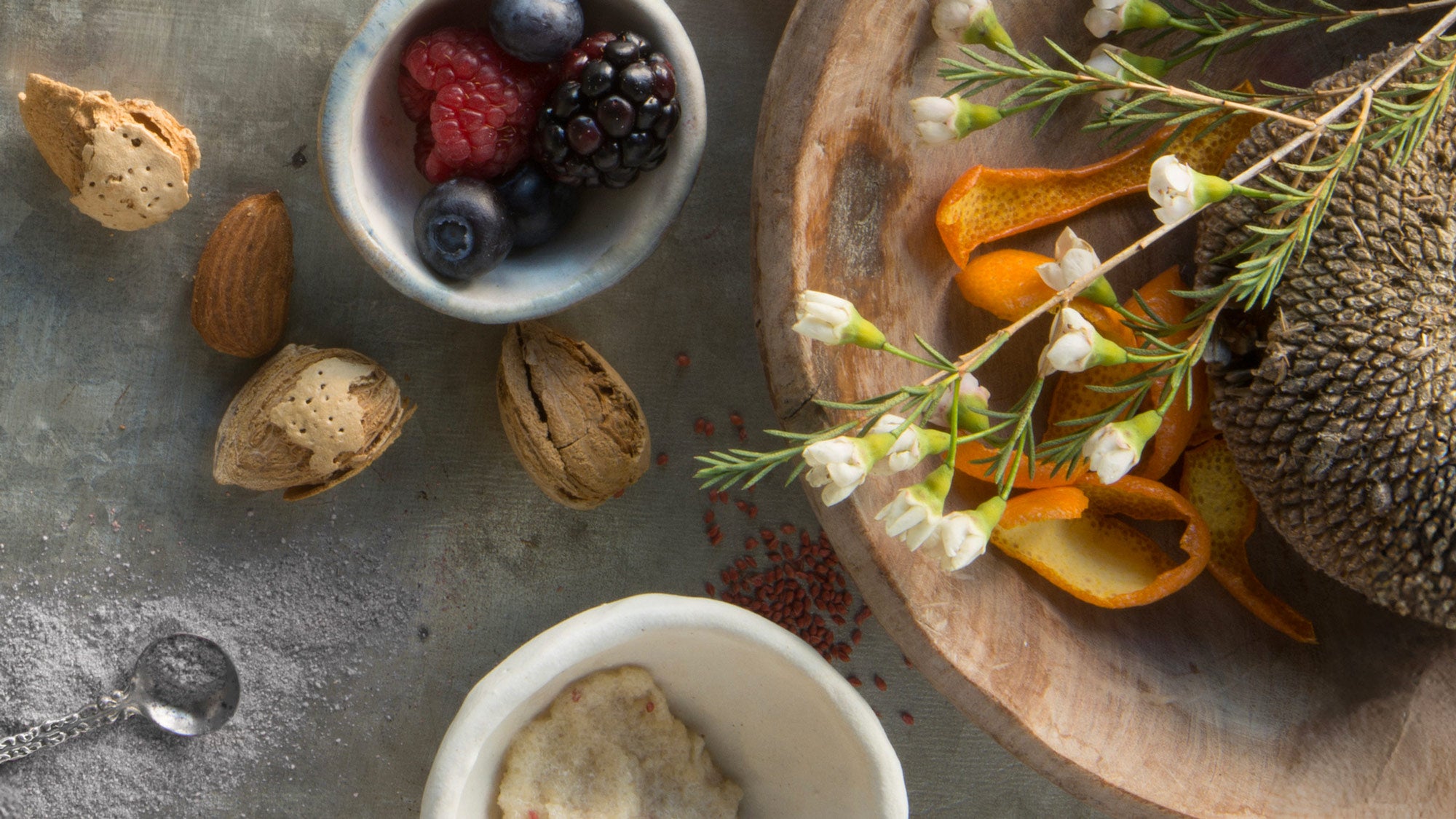 Assorted nuts, berries, and dried fruits on a rustic surface with a wooden board.