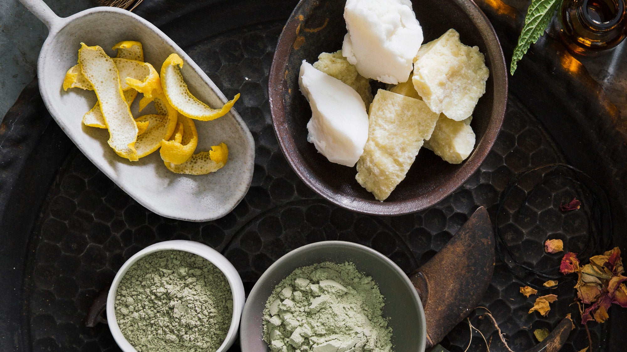 Assorted ingredients including sliced lemons, butter, and green powders on a dark surface.